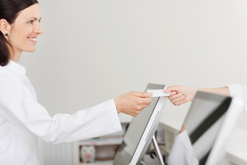 Office Staff Receiving Insurance Card from Patient